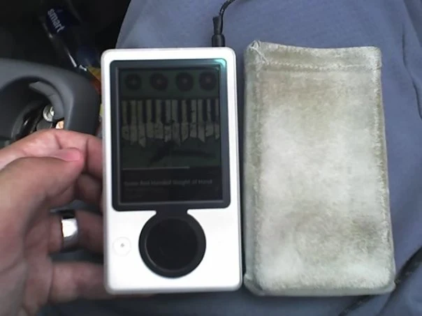 My white first-generation Zune in its case, with the headphone cable plugged in
