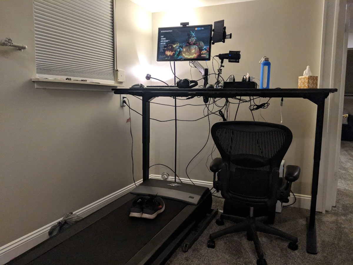My converted treadmill beneath a raised desk, with a monitor, keyboard, and recording equipment above.